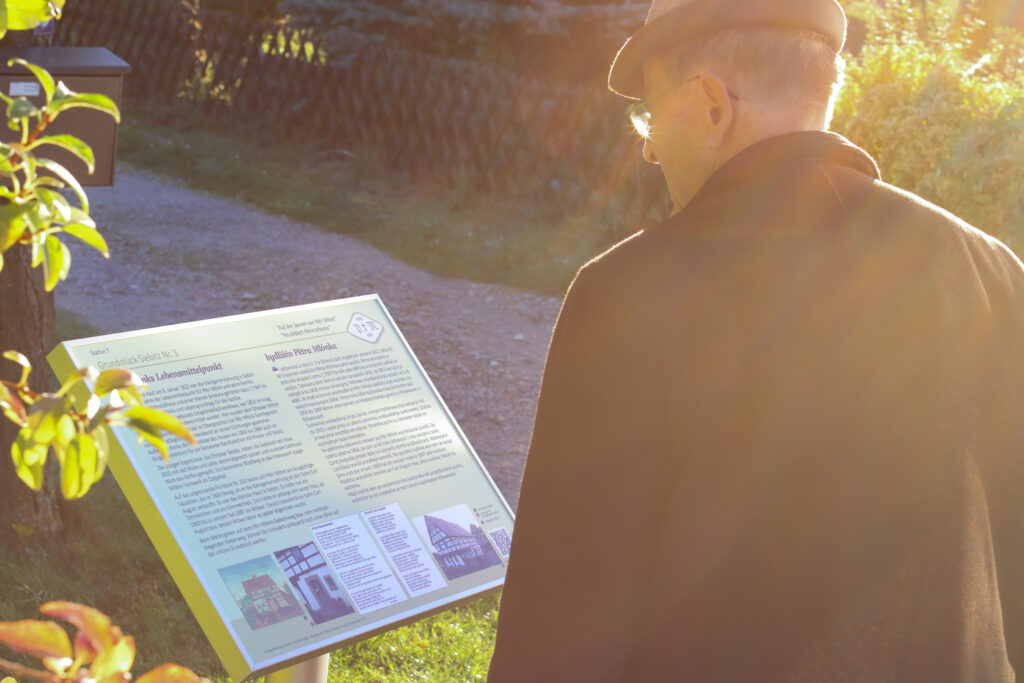Jemand liest die Tafel vor dem Wohnhaus